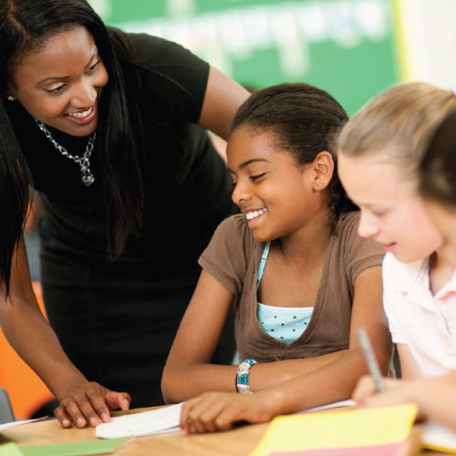 Image of a young woman working with children in a school setting